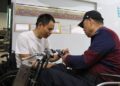 Foto yang diabadikan pada 17 Mei 2025 ini menunjukkan Ke Shuichang (Kiri), seorang teknisi yang menyandang disabilitas di Shanghai, China timur, sedang memperbaiki sebuah ponsel yang rusak. (Xinhua)