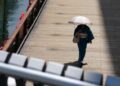 Seorang wanita menyusuri sebuah jalan sambil membawa payung di Osaka, Jepang, pada 10 Juli 2025. (Xinhua/Jia Haocheng)
