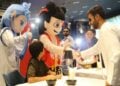 Seorang pria berjabat tangan dengan karakter berkostum Ne Zha saat pemutaran perdana film animasi China "Ne Zha 2" di Dubai, Uni Emirat Arab (UEA), pada 15 Juli 2025. (Xinhua/Wen Xinnian)