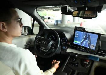 Seorang staf keamanan mengamati saat Robotaxi dari Pony.ai, penyedia solusi kemudi otonomos asal China, mengemudi secara otomatis di sekitar Canton Tower, ikon Kota Guangzhou, Provinsi Guangdong, China selatan, pada 11 Maret 2025. (Xinhua/Deng Hua)